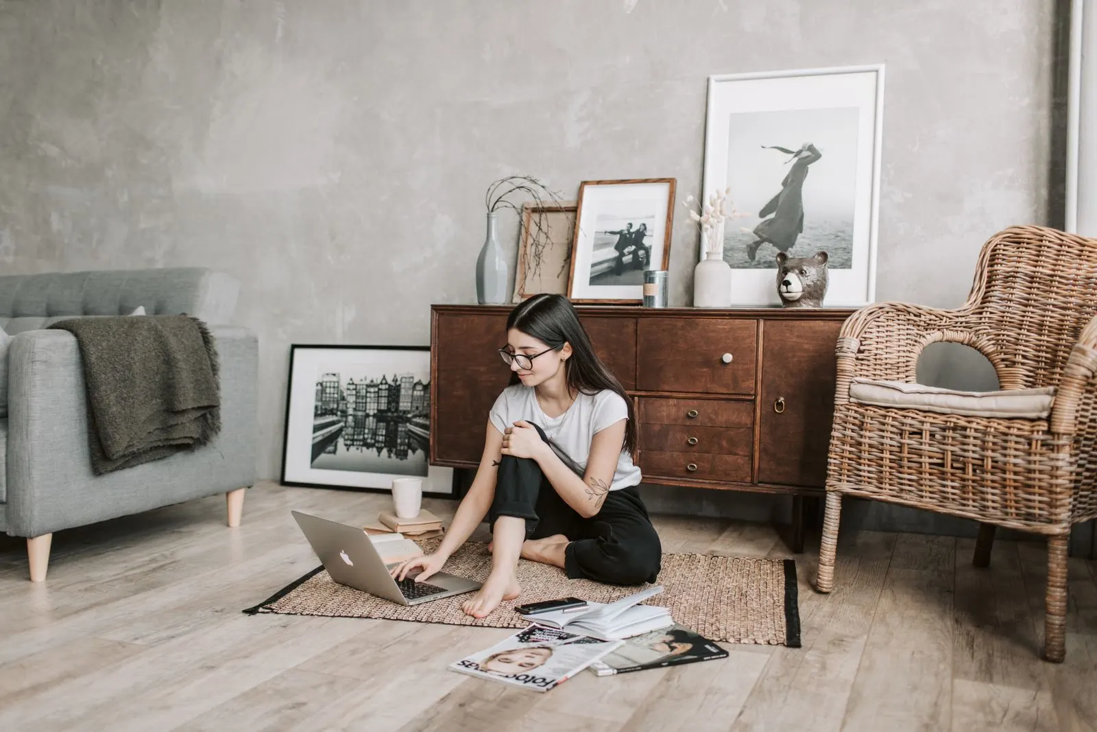 Young woman sitting on the floor of her living room using a laptop